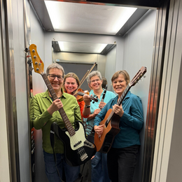 Gruppe von 4 lachender Frauen mit Musikinstrumenten im Fahrstuhl